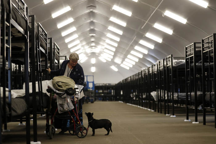 Verna Vasbinder prepares her new bunk in downtown San Diego's Temporary Bridge Shelter for the homeless in December 2017 as her dog, Lucy Lui, looks on. (AP Photo/Gregory Bull)