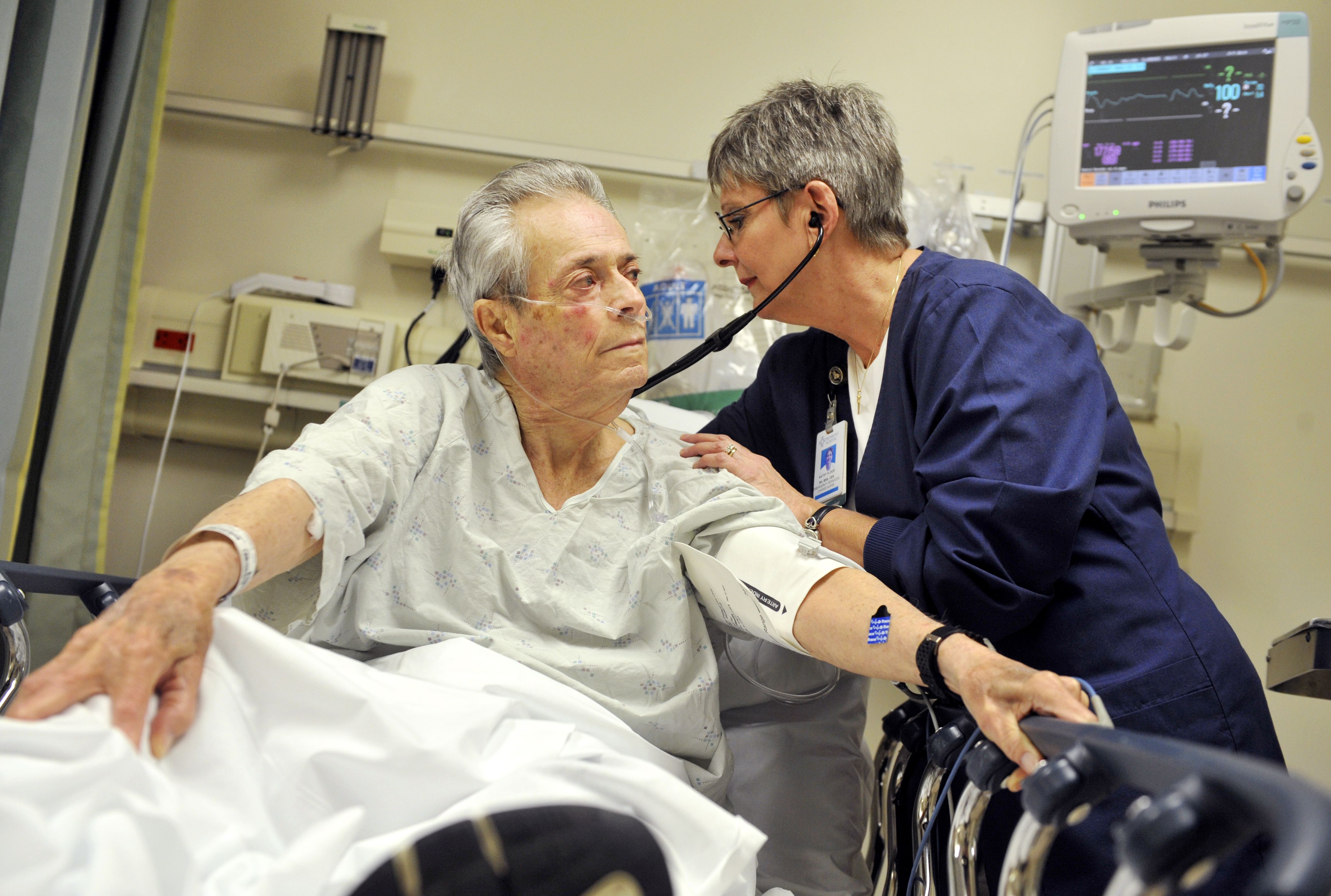 Piedmont Hospital nurse Kathy Flood (right) listens to patient Clarence Dee Holland's breathing to check for signs of pneumonia.