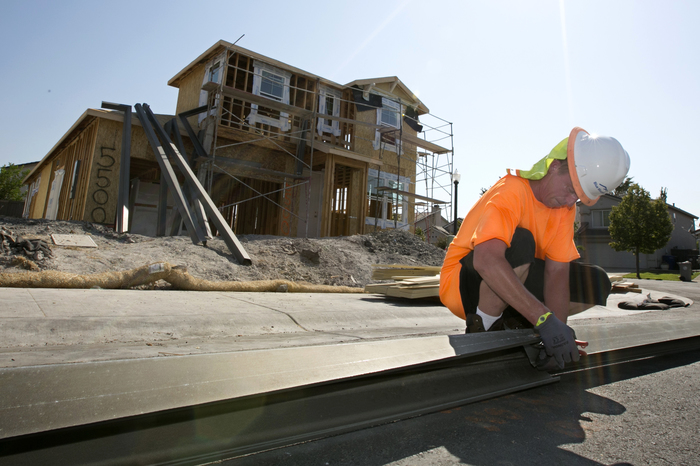 In this photo taken Wednesday, Aug. 16, 2017, sheet metal worker Benjamin Voget prepares to install a gutter on a home under construction in Sacramento. (AP Photo/Rich Pedroncelli)