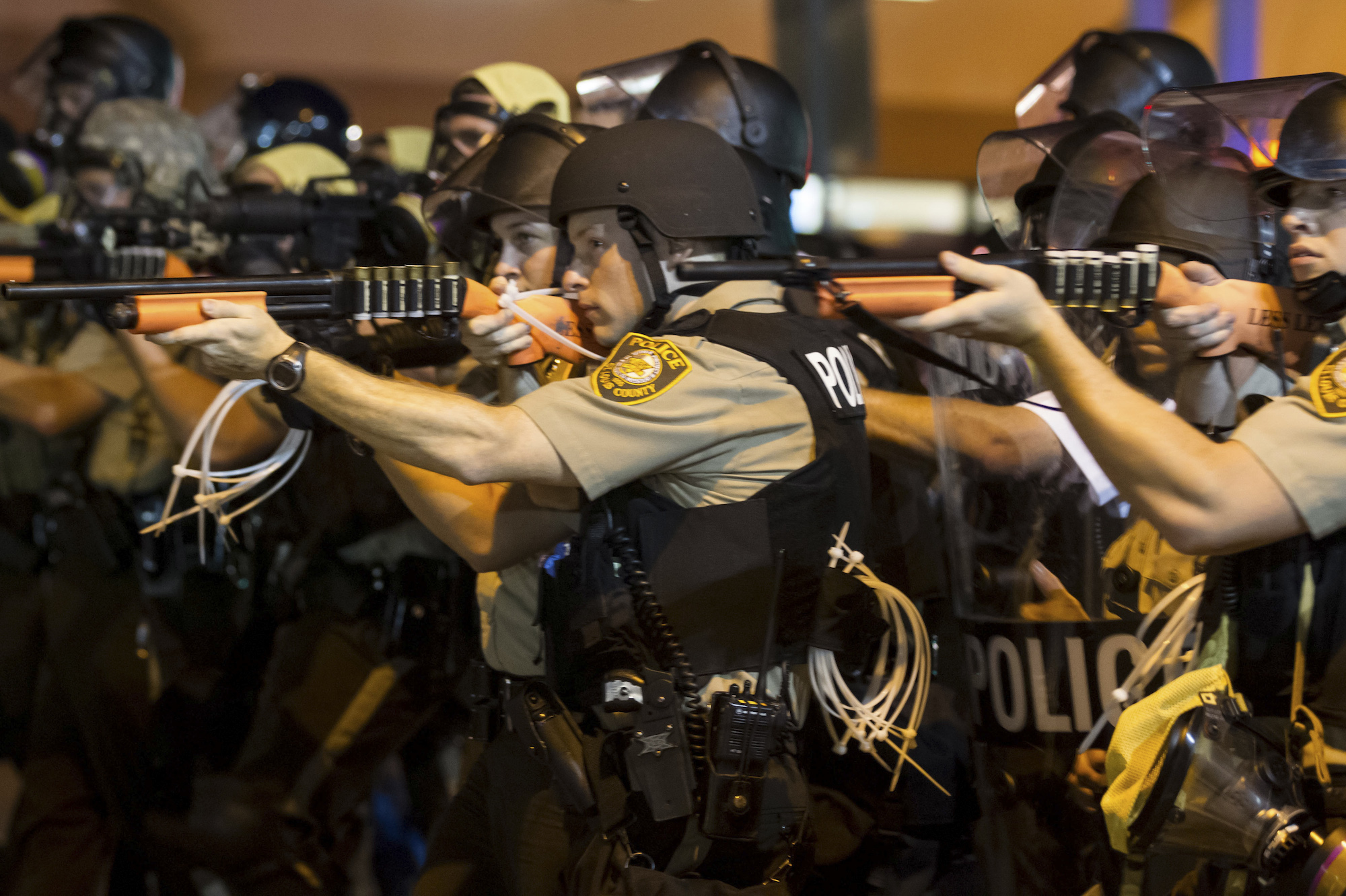 Police aim their weapons and make their way down West Florissant Avenue, pushing protesters north on the street in Ferguson, Mo., the night of Aug. 18, 2014. (New York Times)