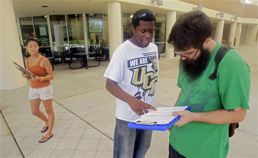 In this July 31, 2012, photo, Aubrey Marks, left, watches Jordan Allen, center, as he helps student Casey Eirhstaedt, right, register to vote at the University of Central Florida in Orlando, Fla. (AP)