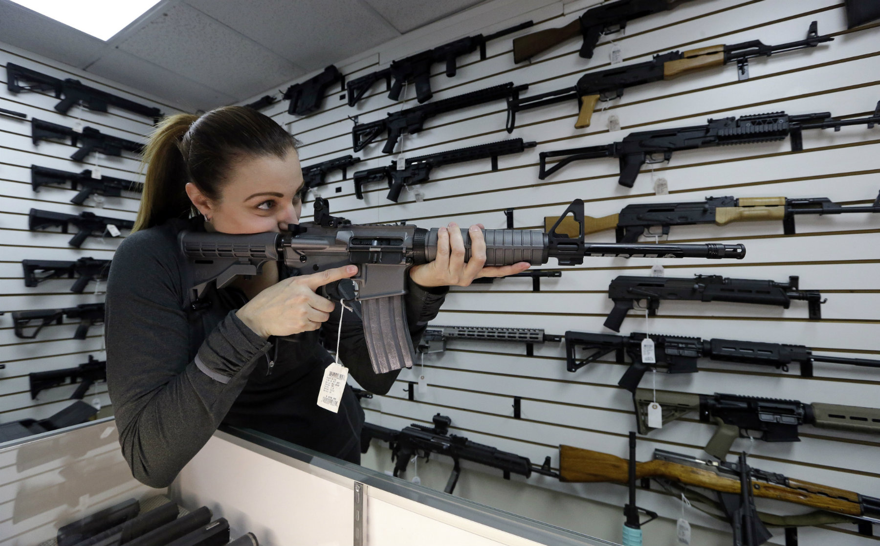 Gun shop owner Tiffany Teasdale-Causer points a Ruger AR-15 semi-automatic rifle in Lynnwood, Wash. (AP Photo/Elaine Thompson)